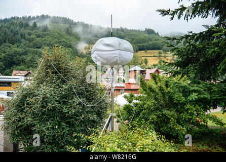 Mobile Meteostation mit Häusern von Ottenhofen im Schwarzwald, Deutschland im Hintergrund und grüne Wälder mit Nebel bedeckt Stockfoto