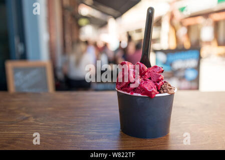 Schokolade und Berry Gelato Eis in schwarzem Papier Schale auf holztisch vor der Eisdiele. Stockfoto