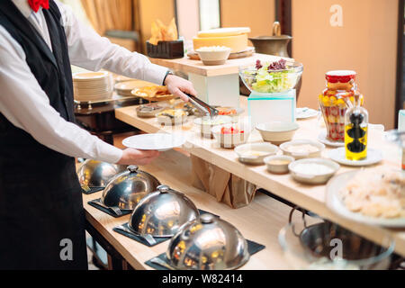 Sauerkraut. Das Frühstück im Hotel oder im Restaurant. Der Kellner sieht das Sauerkraut in die Schüssel. Stockfoto