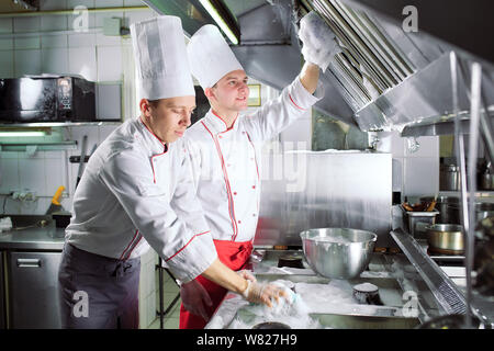 Sanitär Tag im Restaurant. Wiederholt waschen Sie Ihren Arbeitsplatz. Köche waschen Backofen, Herd und Dunstabzugshaube im Restaurant. Stockfoto