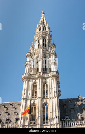 Brüssel, Belgien, 22. Juni 2019: Nahaufnahme von grauen Stein Turm des Rathauses mit belgischer Flagge auf Grand Place gegen den blauen Himmel. Golden Saint Michael st Stockfoto