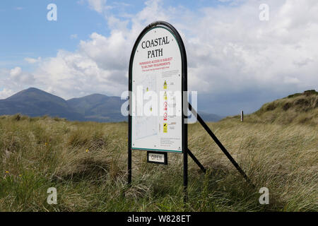 Regeln und Vorschriften über das Wandern durch MOD Land auf dem Küstenpfad Schild an der Grafschaft Down Coast bei Ballykinler, mit Bergen von Mourne hinter. Stockfoto