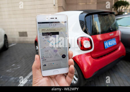 Eine chinesische Benutzer bereitet die TOGO App auf seinem Smartphone den QR-Code zu scannen ist ein Mercedes-Benz Smart Fortwo von Auto-sharing Service TOGO auf Stockfoto