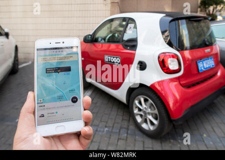 Eine chinesische Benutzer bereitet die TOGO App auf seinem Smartphone den QR-Code zu scannen ist ein Mercedes-Benz Smart Fortwo von Auto-sharing Service TOGO auf Stockfoto