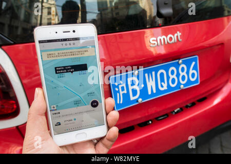Eine chinesische Benutzer bereitet die TOGO App auf seinem Smartphone den QR-Code zu scannen ist ein Mercedes-Benz Smart Fortwo von Auto-sharing Service TOGO auf Stockfoto