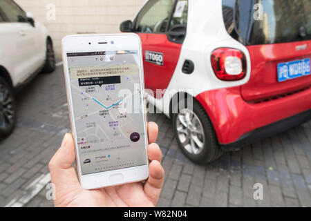 Eine chinesische Benutzer bereitet die TOGO App auf seinem Smartphone den QR-Code zu scannen ist ein Mercedes-Benz Smart Fortwo von Auto-sharing Service TOGO auf Stockfoto