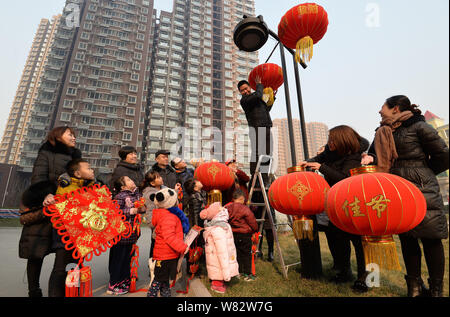 Lokale chinesische Bewohner beobachten ein freiwilliger Aufhängen rote Laternen auf einer Laterne die kommende Frühjahr Festival oder das Chinesische Neue Jahr (Ja zu feiern. Stockfoto