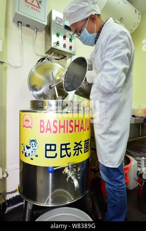 Chinesische cattleman Zeng Bo, ein Doktorat Inhaber, die in der Tierernährung von der Chinesischen Akademie der Wissenschaften, sterilisiert Milch in seine Rinder Farm in Daxiawei vil Stockfoto