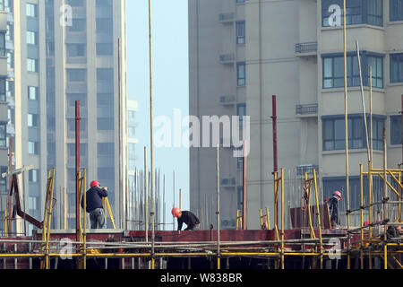 Chinesische Wanderarbeiter ein hohes Gebäude auf der Baustelle eine Wohn- Projekt in Huaian Stadt konstruieren, East China Stockfoto