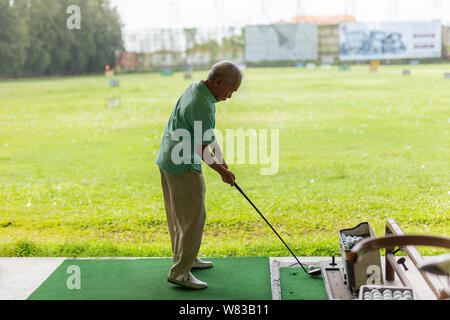 Bangkok Thailand - älterer Mann Übung üben sein Golf an der Golf Driving Range. Stockfoto