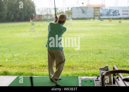 Älterer mann Übung üben sein Golf schwingen am golf driving range. Stockfoto