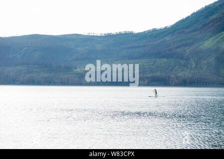 Junges Mädchen Stand up Paddle Boarding auf einem See McDonald im Glacier National Park Stockfoto