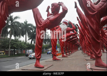 Red Bruce Lee Skulpturen verkleidet als Weihnachtsmann abgebildet, die außerhalb der Creative Industry Park in Foshan City, South China Guangdong Provinz, 21 Dez Stockfoto