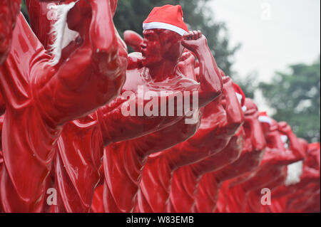 Red Bruce Lee Skulpturen verkleidet als Weihnachtsmann abgebildet, die außerhalb der Creative Industry Park in Foshan City, South China Guangdong Provinz, 21 Dez Stockfoto