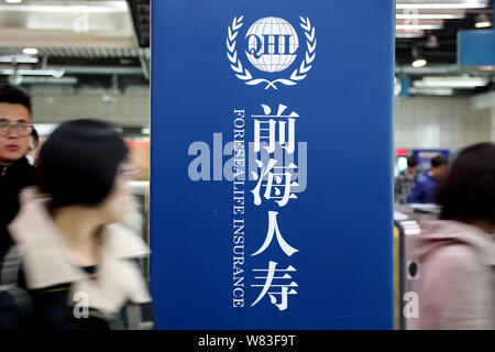 ---- Passagiere vorbei eine Anzeige für Foresea Lebensversicherung (QHL) an einer U-Bahn-Station in Shanghai, China, 7. Dezember 2014. Chinas insura Stockfoto