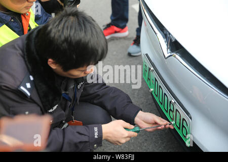 Ein chinesischer Mitarbeiter der lokalen Fahrzeug Verwaltung installiert eine neue Energie Fahrzeug Kennzeichen auf einem Tesla Model X elektrische SUV in Shang Stockfoto