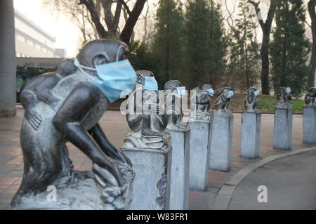 Stein monkey Skulpturen werden gesehen, das Tragen von Gesichtsmasken in schweren Smog in Beijing Zoo in Peking, China, 19. Dezember 2016. In erdrosselnden Smog versenkte, einige Stockfoto