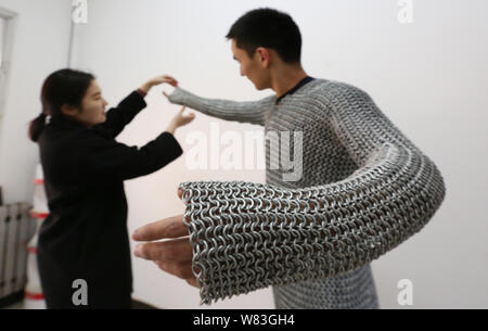 Chinesischer student Hasimu, rechts, ist von einem Freund auf seine hausgemachten mail Rüstung aus 12.000 Ringen aus Stahl in seinem Zimmer im Wohnheim an der Xidian Universität zu setzen, half Stockfoto