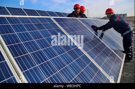 ------ Chinesische Arbeiter installieren Solaranlagen auf dem Dach eines Hauses in Duzhuang Duzhuang Dorf, Stadt, Qinhuangdao Stadt, in Nordchina Hebei provi Stockfoto