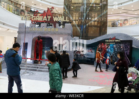 Menschen gehen vorbei an Installationen und Poster Werbung der Film "Die große Wand" am Wanda Plaza in Kunshan City, der Provinz Hubei in Zentralchina, 10. Stockfoto