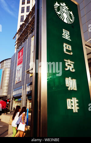 ---- Fußgänger vorbei an einer Werbung für Kaffee von Starbucks in Tianjin, China, 10. September 2014. Starbucks sagte, daß es erwartet von seinen schnell wachsenden Stockfoto