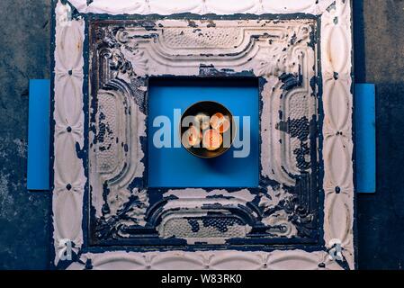 Abstrakte Fotografie von metallbeschichteten Mandarinen in einer Schüssel auf Eine blaue und hölzerne Oberfläche Stockfoto