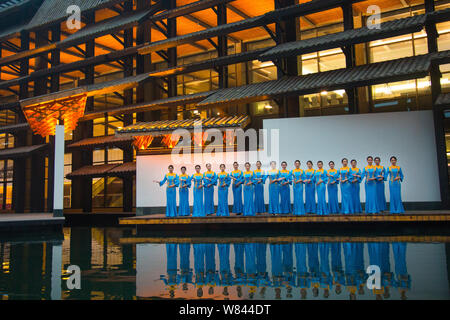 Freiwillige tragen (qipao Cheongsam) mit Phoenix Dekoration posieren vor dem wuzhen Internet International Convention Center vor der bevorstehenden Stockfoto