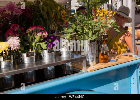 Ein Anbieter von Gipsy blaue Blumen Einblicke rund um ihr Fahrzeug mit blumensträussen zum Verkauf an die Landwirte Markt in der Innenstadt von Fort Wayne, Indiana, USA gefüllt Stockfoto