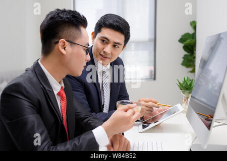 Taille-up Portrait von zwei schöne und Geschäftsleute im Anzug am Tisch sitzen mit Laptop im Büro, Reden und schauen auf einander, während di Stockfoto