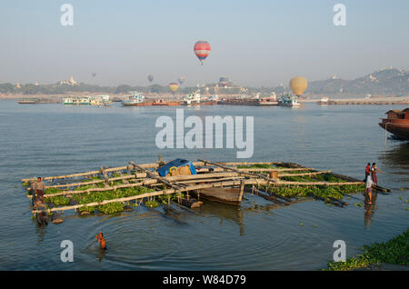 Luftballons Touristen, fliegen Sie über den Irrawaddy Fluss mit Protokollierung Lastkähne überfüllt Stockfoto