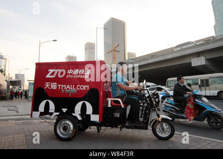 ---- Eine chinesische Kurier von ZZUM Express Fahrten ein elektrisches Dreirad mit dem Logo der Alibaba online shopping site Tmall.com Pakete zu liefern. Stockfoto