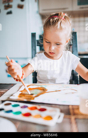 Schöne blonde Mädchen malen Mit Pinsel und Wasser Farben in der Küche. Kid Aktivitäten Konzept. Close Up. Getönt Stockfoto