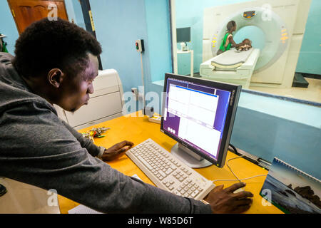 Ein Arzt untersucht, ein Mädchen (3 Jahre alt) leidet unter Hydrocephalus (Spina Bifida) in einem CT-Scanner (Computertomografie) im St. Clare Klinik der deutsche Missionar Arzt Dr. med. Thomas Brei in Mwanza, Tansania, Afrika Stockfoto