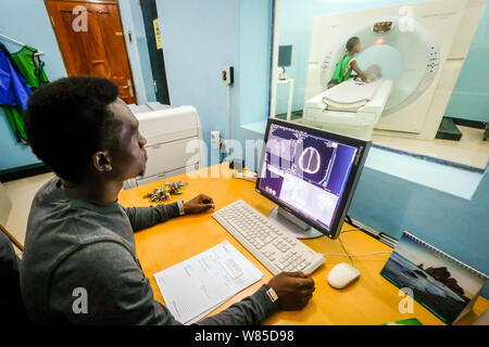 Ein Arzt untersucht, ein Mädchen (3 Jahre alt) leidet unter Hydrocephalus (Spina Bifida) in einem CT-Scanner (Computertomografie) im St. Clare Klinik der deutsche Missionar Arzt Dr. med. Thomas Brei in Mwanza, Tansania, Afrika Stockfoto