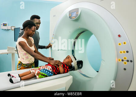 Arzt mit m Mutter und ihrer Tochter (3 Jahre alt), die Leiden von hydrocephalus (Spina bifida) in einem CT-Scanner (Computertomographie) an der katholischen St. Clare Klinik der deutsche Missionar Arzt Dr. med. Thomas Brei in Mwanza, Tansania, Afrika Stockfoto