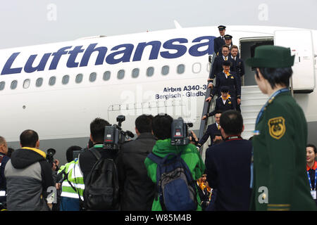 ---- Eine Polizistin wacht als Chinesische Stewardessen deplane ein Flugzeug der Lufthansa an der Qingdao Liuting zum Internationalen Flughafen Stockfoto