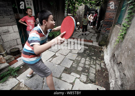 Die jungen chinesischen Jungen spielen Tischtennis auf dem Boden in einer engen Gasse in einem Hutong in Ji'Nan, der ostchinesischen Provinz Shandong, den 2. August 2016. Stockfoto