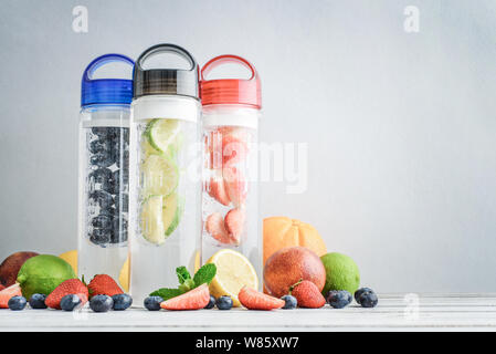 Infundiert detox Wasser in Flaschen mit frischen Früchten und Beeren auf hellblauem Hintergrund Stockfoto