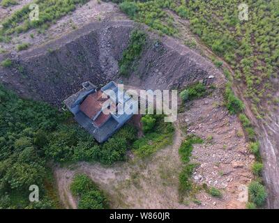 Ein Nagel Haus, dessen Besitzer weigerte sich wegen Streitigkeiten über Entschädigung details zu verschieben ist in einer Grube auf der Baustelle eines industriellen isoliert Stockfoto