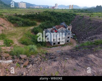 Ein Nagel Haus, dessen Besitzer weigerte sich wegen Streitigkeiten über Entschädigung details zu verschieben ist in einer Grube auf der Baustelle eines industriellen isoliert Stockfoto