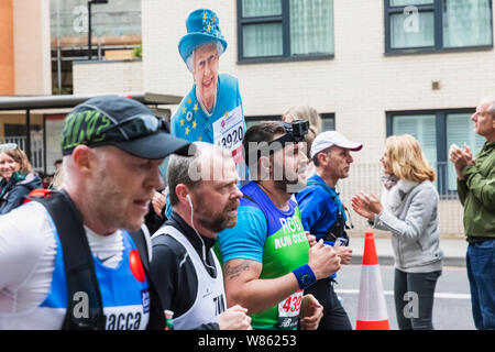 England, London, London Marathon 2019, Gruppe von Läufern und Pappe Ausschnitt von Königin Elizabeth II. Stockfoto