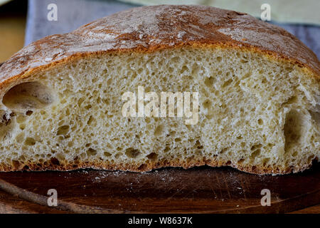 Nahaufnahme von frisch gebackenem Brot im rustikalen Stil/Frischer runde Brot mit einer schönen Kruste liegt auf einem Holzbrett/hausgemachtes Brot Stockfoto