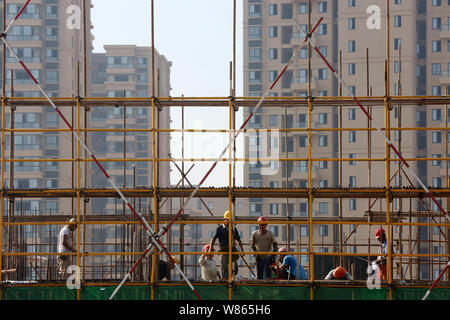 Chinesische Wanderarbeiter ein hohes Gebäude auf der Baustelle eine Wohn- Projekt in Huaian Stadt konstruieren, East China Stockfoto