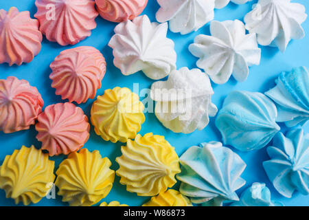 Mehrfarbige meringue auf einem blauen Pastellfarben Hintergrund. Leckere bunte handgemachte Dessert. Stockfoto