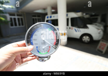 Ein medizinischer Arbeiter zeigt ein Thermometer zeigt die Temperatur über 50 Grad Celsius unter der sengenden Sonne in einem Krankenhaus in Shanghai, China, 23 J Stockfoto