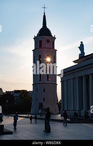 Vilnius, Litauen. Abend am Platz der Kathedrale mit Glockenturm auf dem Hintergrund und den Sonnenuntergang mit Silhouette von Menschen zu Fuß Stockfoto