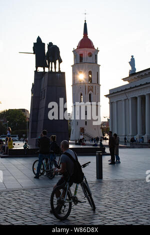 Vilnius, Litauen. Abend am Platz der Kathedrale mit Glockenturm auf dem Hintergrund und den Sonnenuntergang mit Biker Stockfoto