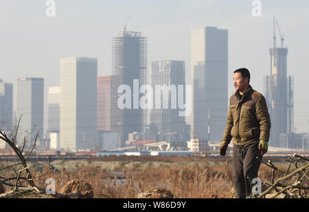 ---- Ein chinesischer Arbeiter als er pflanzen Bäume auf einem Grundstück in der Nähe von High-rise Office Gebäude im Bau in Yujiapu Financial District in Fach Stockfoto