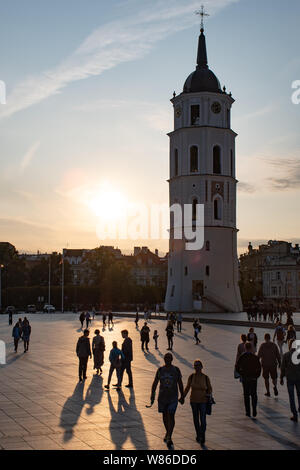 Vilnius, Litauen. Abend am Platz der Kathedrale mit Glockenturm auf dem Hintergrund und den Sonnenuntergang mit Silhouette von Menschen zu Fuß Stockfoto