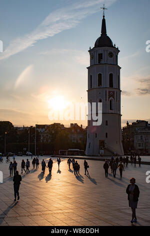 Vilnius, Litauen. Abend am Platz der Kathedrale mit Glockenturm auf dem Hintergrund und den Sonnenuntergang mit Silhouette von Menschen zu Fuß Stockfoto